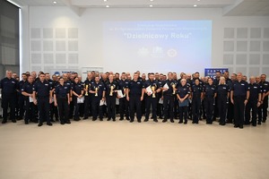 Duża grupa policjantów pozująca w auli do zdjęcia