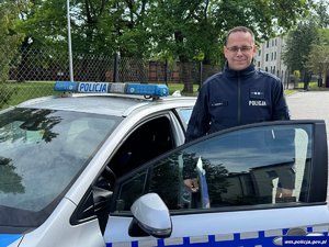 Uśmiechnięty policjant w drzwiach radiowozu