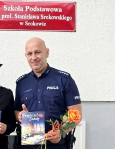 Policjant z kwiatem i laurką w ręku