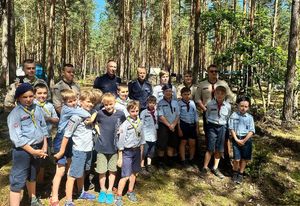 Grupa harcerzy praz dwóch policjantów pozująca do zdjęcia w kompleksie leśnym
