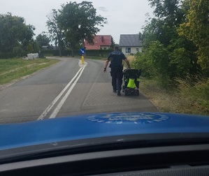 Policjant pchający jezdnią elektryczny wózek inwalidzki