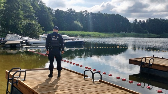 Umundurowany policjant stojący na pomoście jeziora