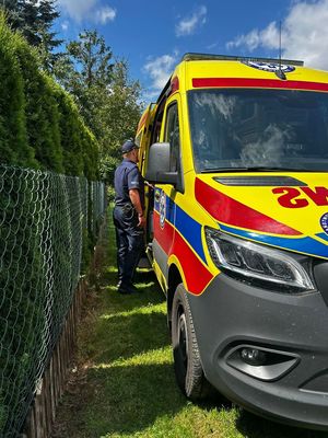 Karetka pogotowia a przy niej stojący umundurowany policjant