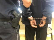 Umundurowany policjant trzyma zatrzymanego mężczyznę