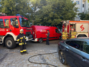 Policjantka, strażacy i wozy straży pożarnej na miejscu pożaru