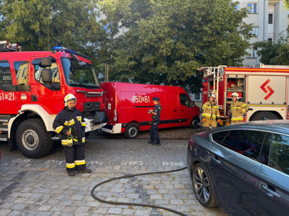Policjantka, strażacy i wozy straży pożarnej na miejscu pożaru