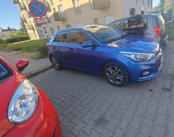 Umundurowany Policjant na ulicy pomiędzy samochodami