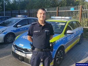 Policjant na tle radiowozu