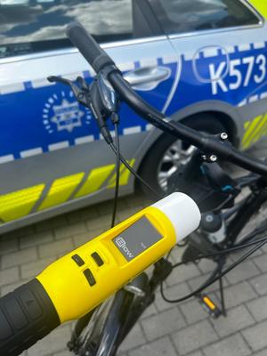 Zdjęcie alkotestu na tle roweru i radiowozu