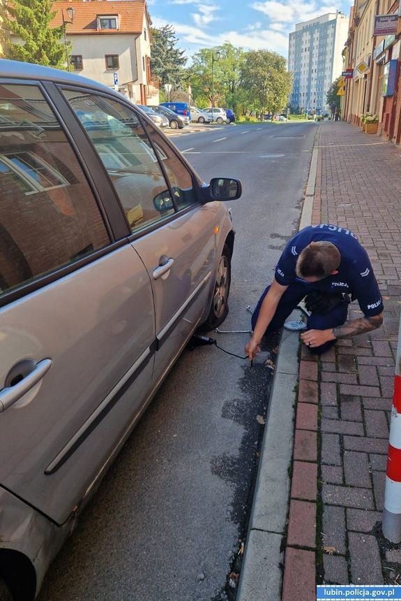 Policjant zmieniający koło w samochodzie na ulicy