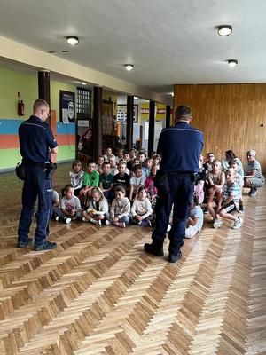 Dwaj policjanci z grupą dzieci na sali gimnastycznej