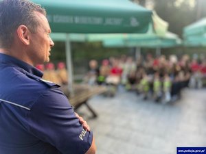 Widziany od tyłu policjant na tle rozmytej grupy ludzi