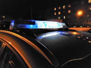 Dach radiowozu z włączoną galeryjką w scenerii nocnej osiedla