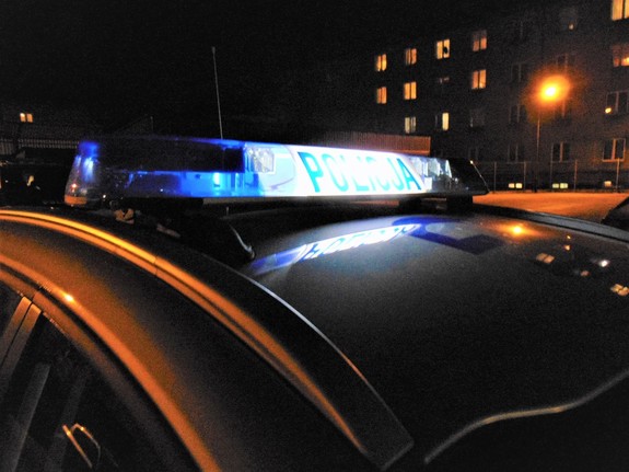 Dach radiowozu z włączoną galeryjką w scenerii nocnej osiedla
