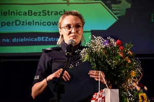 Policjantka z bukietem kwiatów na scenie