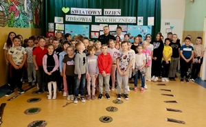 Pozujący do zdjęcia w sali [policjant z grupą dzieci