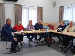 W sali przy stołach konferencyjnych policjant oraz seniorzy