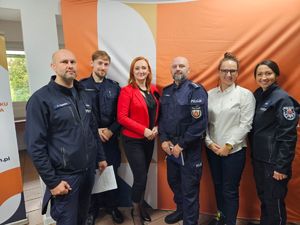 Pozująca do zdjęcia w sali czwórka policjantów oraz dwie kobiety po cywilnemu.