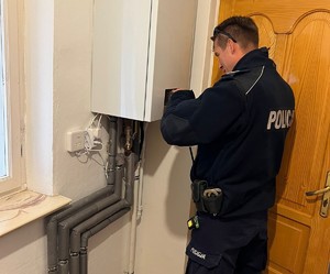 Policjant przy piecu gazowym wiszącym na ścianie