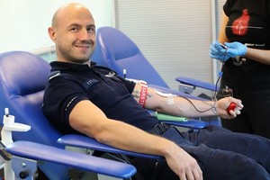 Uśmiechnięty policjant na fotelu podczas oddawania krwi