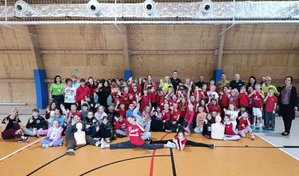 Trójka policjantów, wychowawcy, młodzież i dzieci pozujący do zdjęcia w hali sportowej.