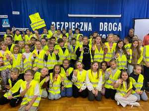 Grupa dzieci w kamizelkach odblaskowych pozująca do zdjęcia