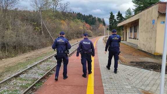 Na leśnym przystanku kolejowym widziani z tyłu policjant oraz dwaj SOKiści.