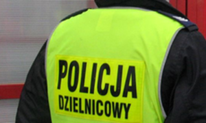Plecy policjanta w odblaskowej kamizelce z napisem policja dzielnicowy