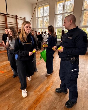 Grupa młodzieży oraz policjant na sali gimnastycznej