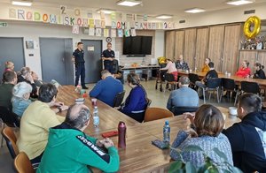 Dwaj policjanci prowadzący spotkanie w świetlicy wypełnionej podopiecznymi domu pomocy