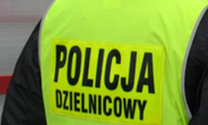 Plecy policjanta w kamizelce z napisem policja dzielnicowy