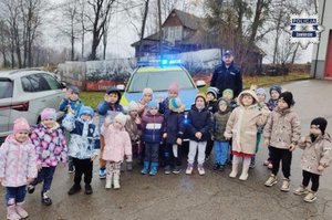 Grupa dzieci pozująca do zdjęcia na tle radiowozu