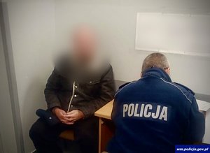 Mężczyzna oraz policjant przy biurku w czasie sporządzania dokumentacji
