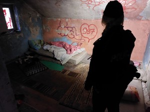 Widziana od tyłu sylwetka policjantki w ciemnym pustostanie