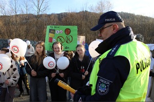 Policjant oraz grupa młodzieży z balonikami w otwartej przestrzeni