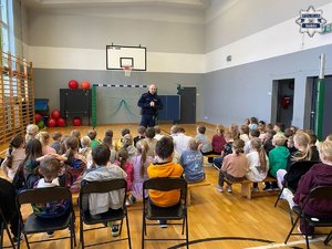 Policjant w trakcie pogadanki dla zgromadzonych w sali gimnastycznej dzieci