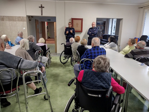 Dwójka policjantów podczas prelekcji w sali wypełnionej starszymi ludźmi