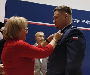 Kobieta przypinająca policjantowi odznaczenie