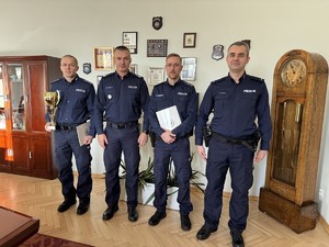 Czterech policjantów z pucharami pozująca do zdjęcia w gabinecie