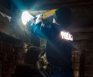 W ciemnej kotłowni policjant świecący latarką