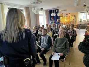 Świetlica wypełniona seniorami i policjantka prowadząca wykład
