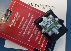 Zdjęcie akt dochodzenia, kodeksu karnego oraz legitymacji policyjnej