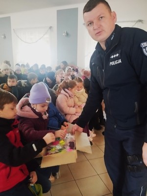 Policjant w sali na tle grupy siedzących dzieci