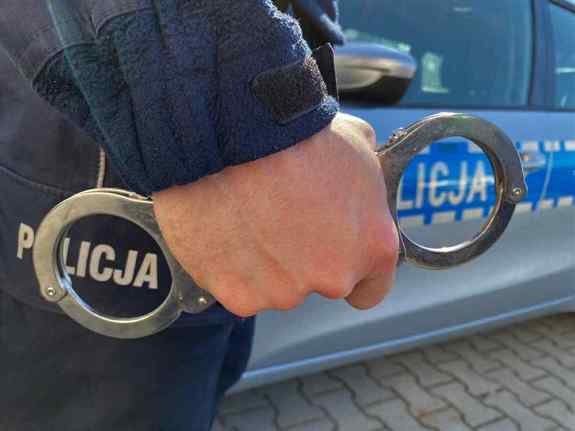 Zbliżenie ręki policjanta trzymającego w ręku kajdanki