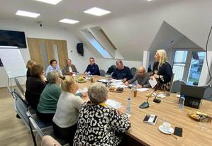 Sala konferencyjna, przy stole kilkanaście osób w tym policjant