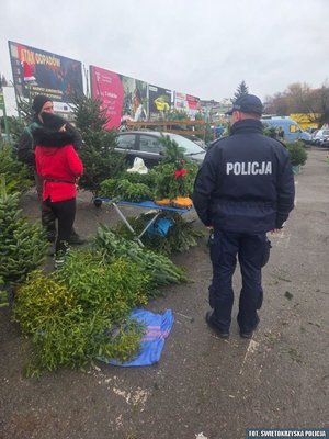 Policjant na tle straganu z choinkami