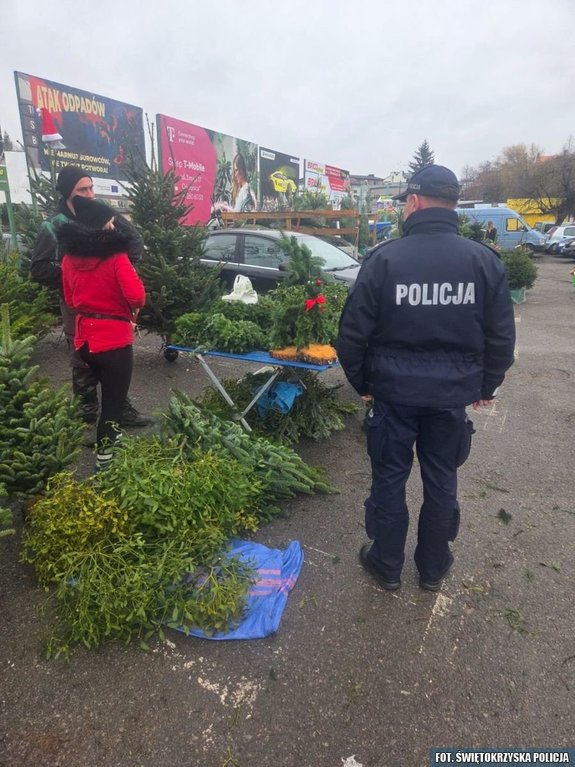 Policjant na tle straganu z choinkami