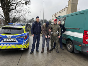 Dwaj policjanci i żołnierz pozujący do zdjęcia z pozorantem na tle radiowozu i pojazdu ŻW