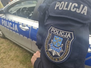 Ujęcie tułowia policjanta na tle radiowozu