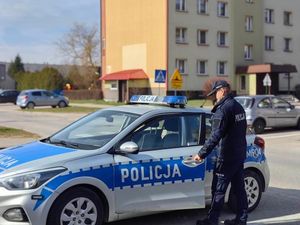 Policjant wsiadający do radiowozu na parkingu osiedlowym